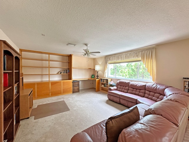 living room featuring a textured ceiling, ceiling fan, and light colored carpet