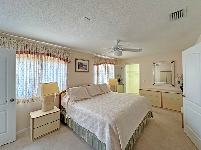 carpeted bedroom featuring a textured ceiling, a spacious closet, ceiling fan, and a closet