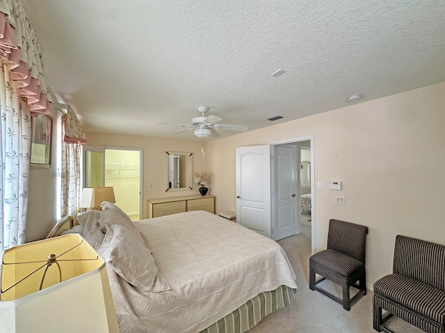 carpeted bedroom with a textured ceiling, ceiling fan, a walk in closet, and a closet