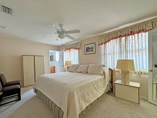 carpeted bedroom featuring ceiling fan and a textured ceiling