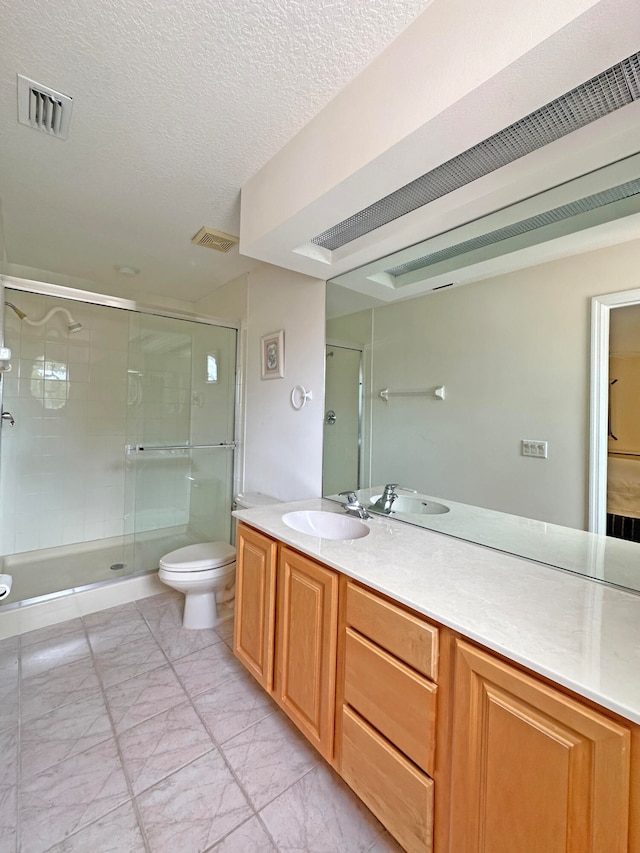 bathroom with vanity, a textured ceiling, toilet, and a shower with door