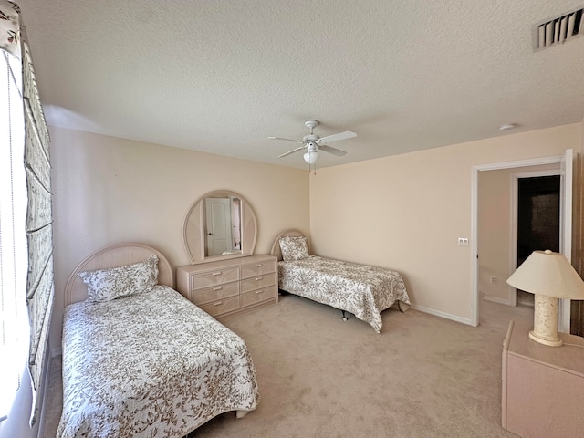 carpeted bedroom with ceiling fan and a textured ceiling