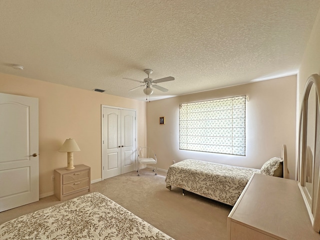 bedroom featuring light carpet, a closet, ceiling fan, and a textured ceiling