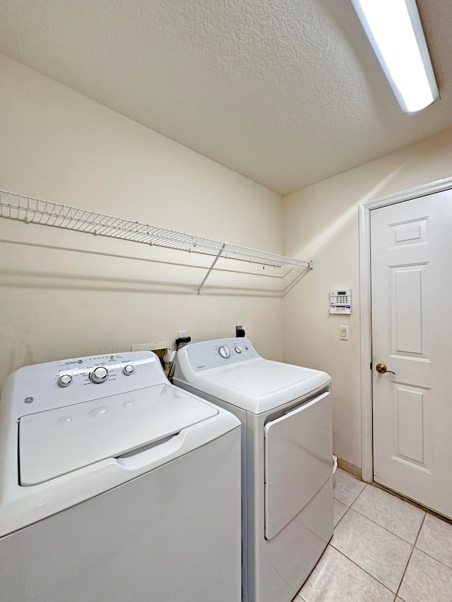 laundry area featuring a textured ceiling, light tile patterned floors, and independent washer and dryer