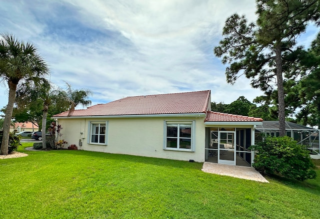 rear view of house featuring a lawn and a sunroom