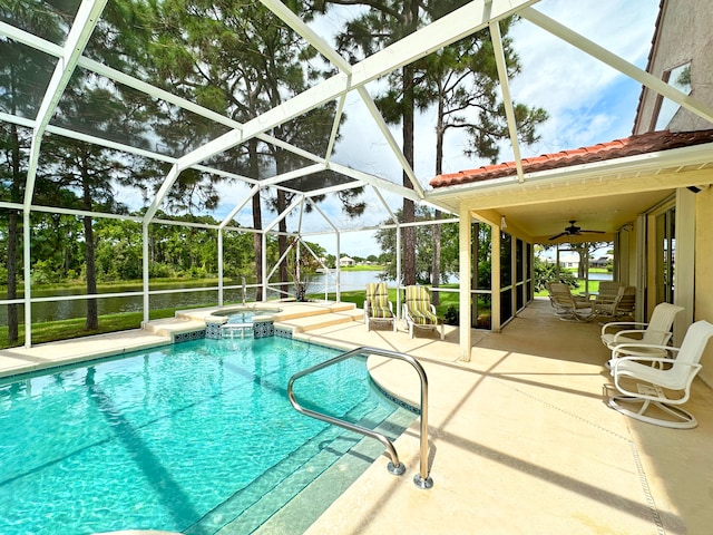 view of swimming pool with a patio, a water view, an in ground hot tub, glass enclosure, and ceiling fan