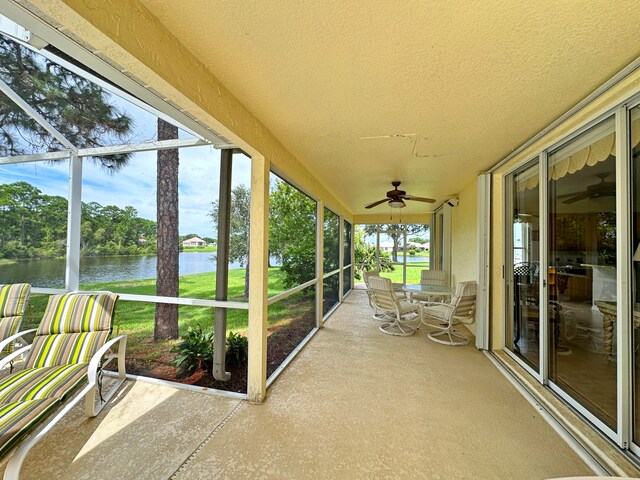 unfurnished sunroom with a water view and ceiling fan