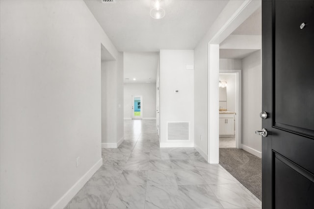 hall with light carpet and a textured ceiling