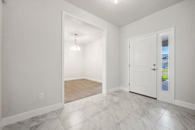 foyer entrance featuring a chandelier, a textured ceiling, and light colored carpet