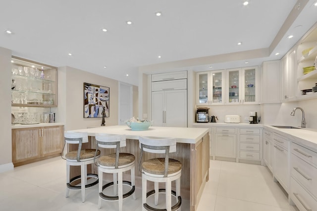 kitchen with white cabinets, a kitchen bar, sink, and a center island