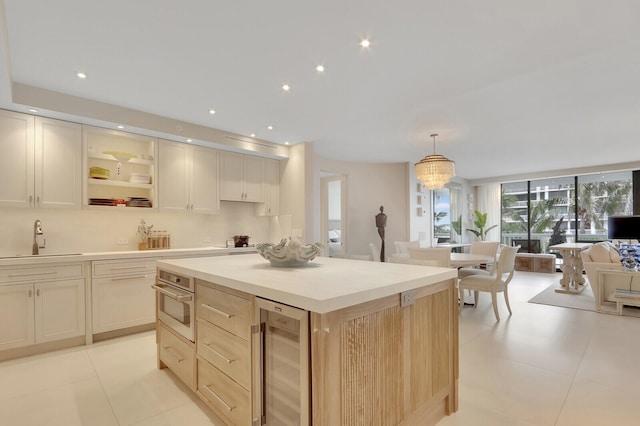 kitchen with wine cooler, pendant lighting, oven, sink, and a notable chandelier