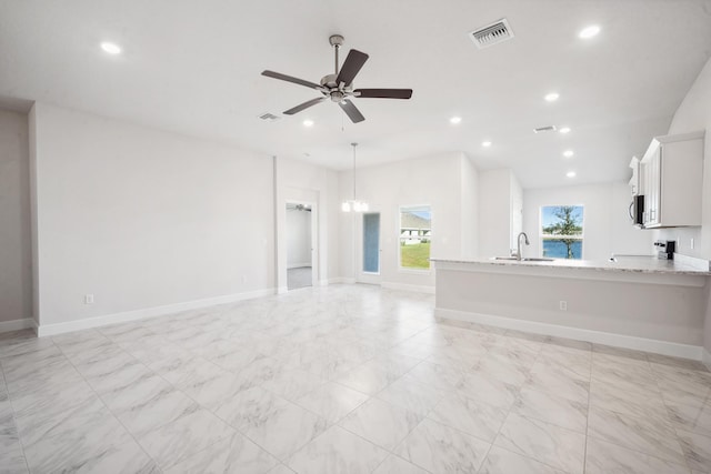 unfurnished living room featuring light carpet, ceiling fan with notable chandelier, and vaulted ceiling