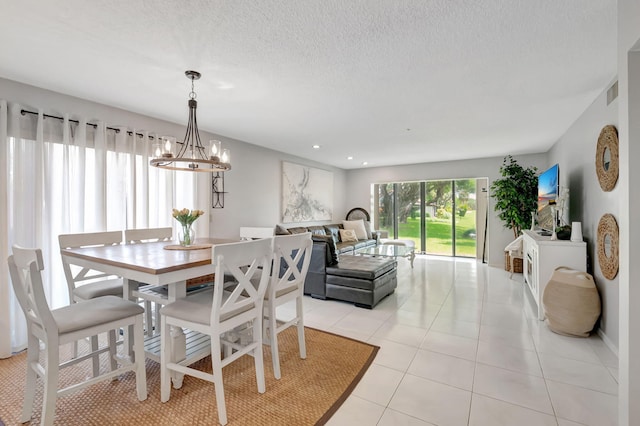 dining space with a notable chandelier, a textured ceiling, and light tile patterned flooring