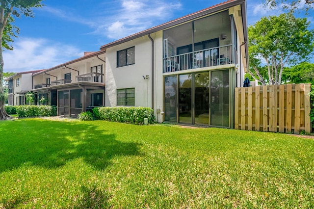 back of property with a lawn and a balcony