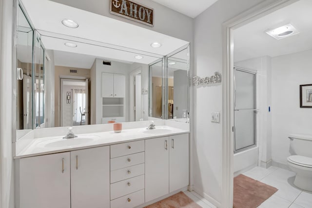 full bathroom with combined bath / shower with glass door, vanity, toilet, and tile patterned floors