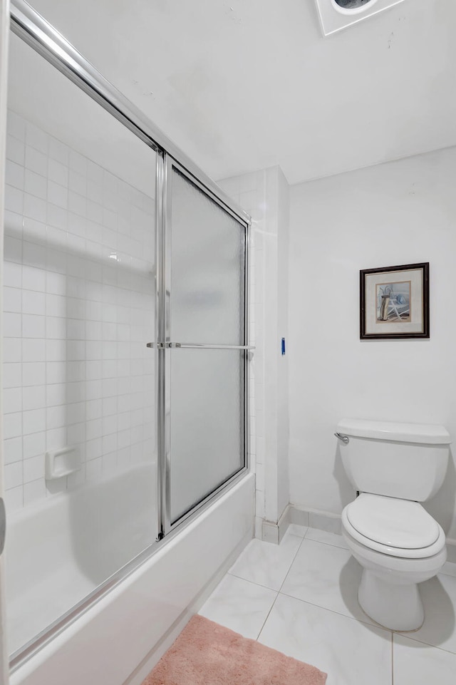 bathroom featuring combined bath / shower with glass door, toilet, and tile patterned floors