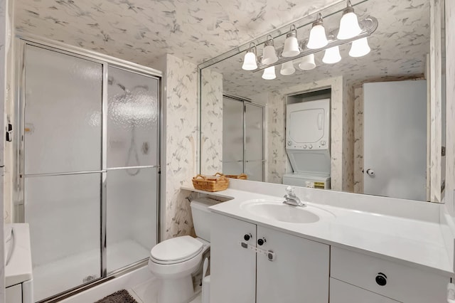 bathroom with stacked washer and clothes dryer, vanity, toilet, and a shower with door