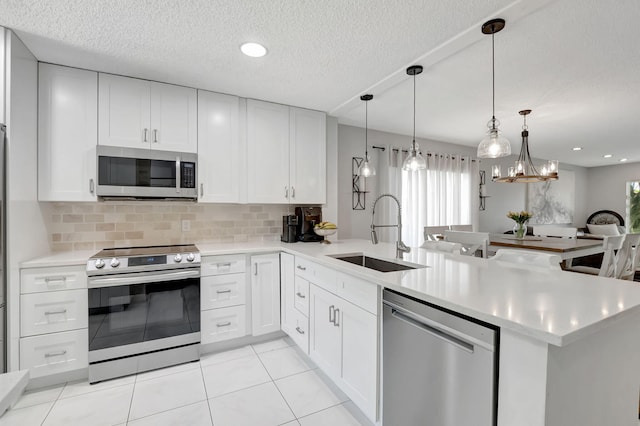 kitchen featuring kitchen peninsula, sink, stainless steel appliances, and white cabinets