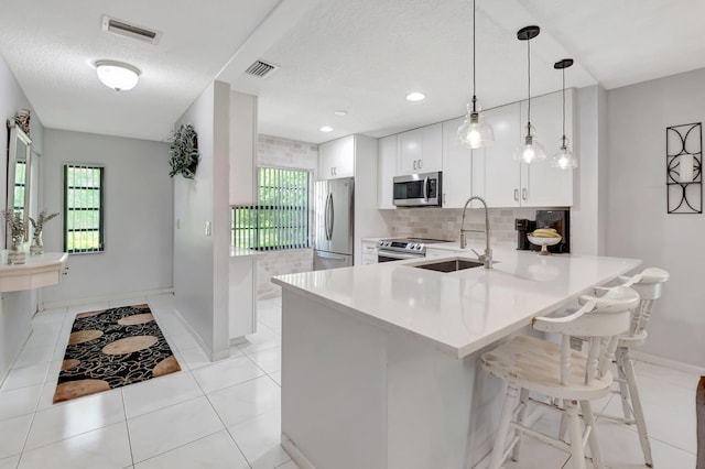 kitchen with a breakfast bar, light tile patterned flooring, sink, white cabinetry, and appliances with stainless steel finishes