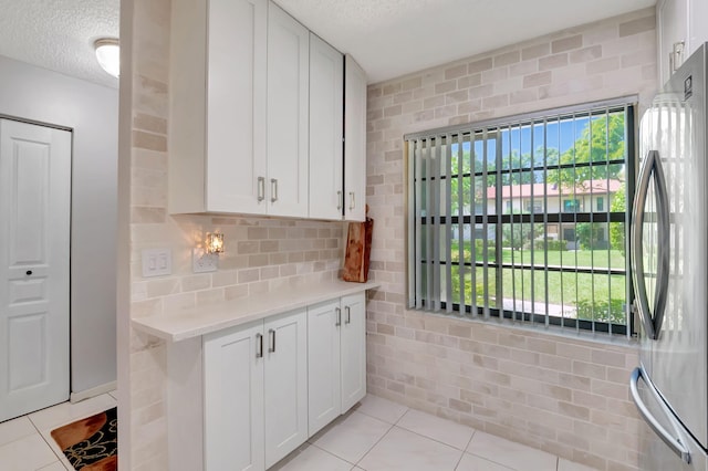 kitchen featuring a textured ceiling, plenty of natural light, and white cabinetry