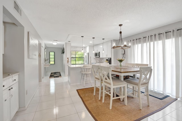 tiled dining area featuring a textured ceiling and a notable chandelier