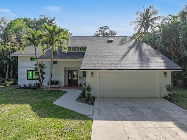 view of front of house with roof with shingles, concrete driveway, an attached garage, and a front yard