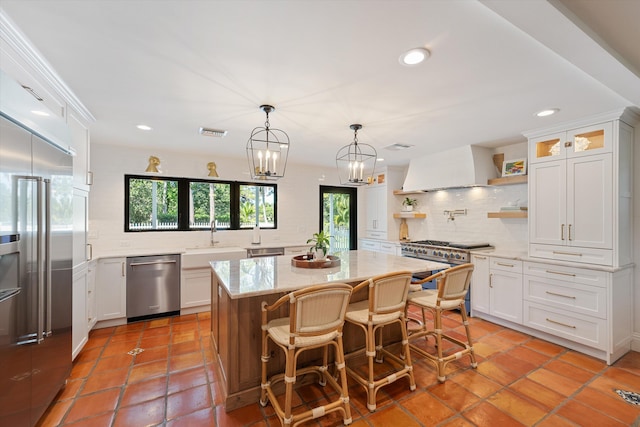 kitchen with a sink, open shelves, premium range hood, high quality appliances, and backsplash