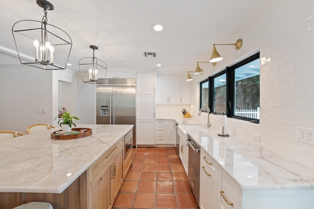 kitchen featuring pendant lighting, visible vents, built in appliances, backsplash, and a kitchen island