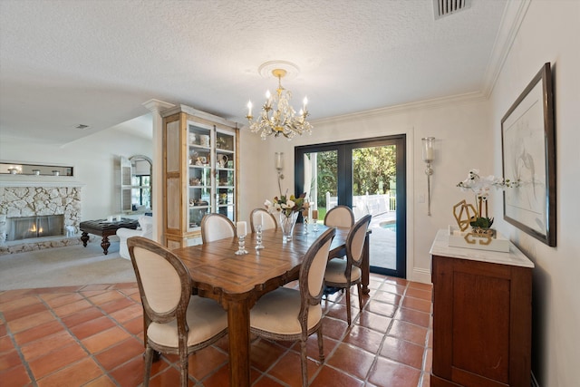 dining space featuring a textured ceiling, a notable chandelier, a fireplace, crown molding, and french doors