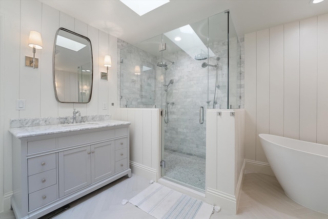 bathroom featuring a skylight, vanity, recessed lighting, a stall shower, and a soaking tub