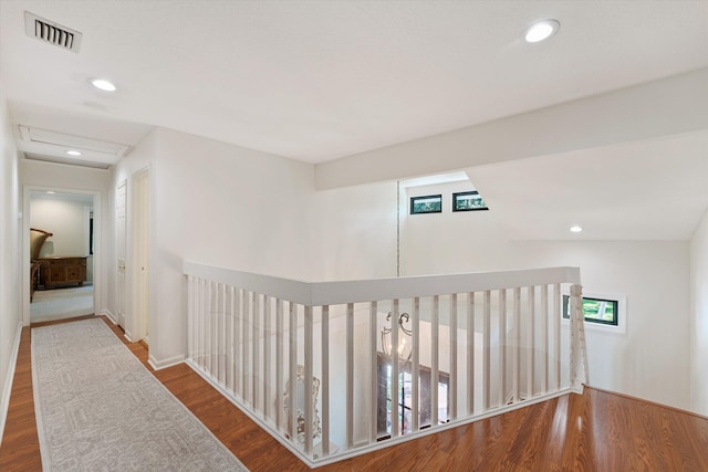 corridor with vaulted ceiling and hardwood / wood-style floors