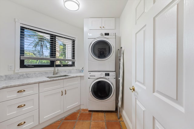 clothes washing area featuring cabinet space, stacked washer / dryer, light tile patterned floors, and a sink