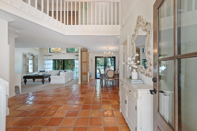 foyer entrance featuring a towering ceiling, an inviting chandelier, french doors, and tile patterned floors