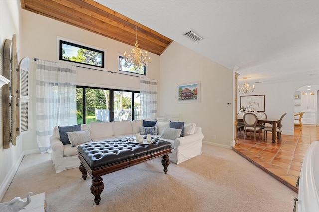 carpeted living room with baseboards, a notable chandelier, visible vents, and arched walkways