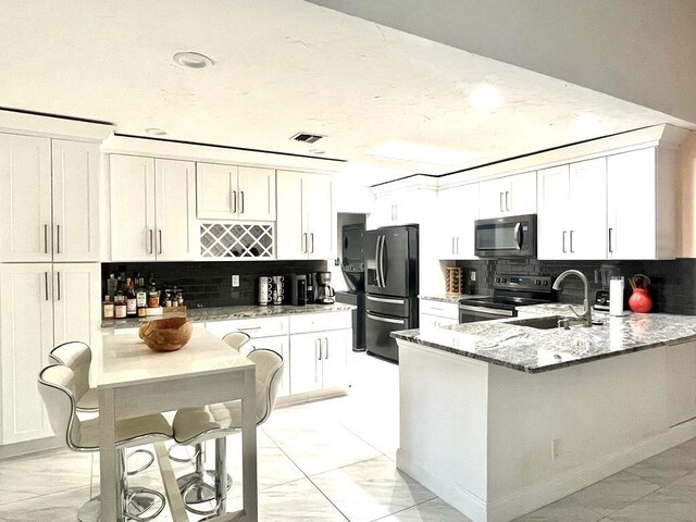 kitchen with black appliances, light stone countertops, decorative backsplash, and white cabinetry