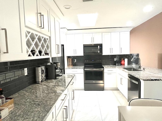 kitchen featuring appliances with stainless steel finishes, decorative backsplash, white cabinetry, and sink