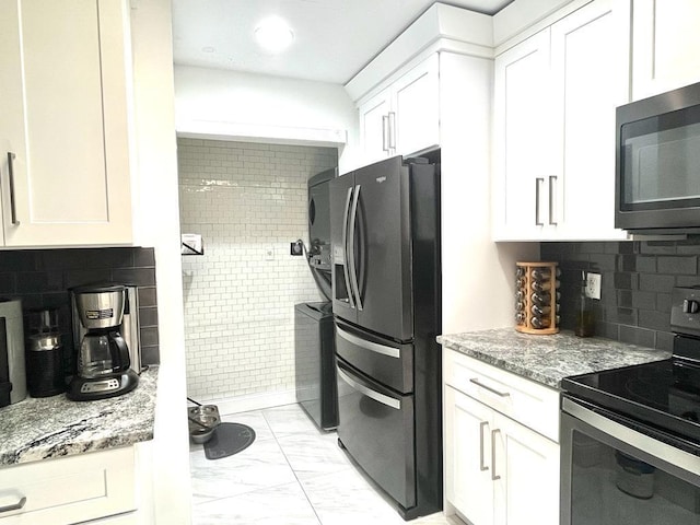 kitchen featuring light stone countertops, backsplash, stainless steel appliances, and white cabinets