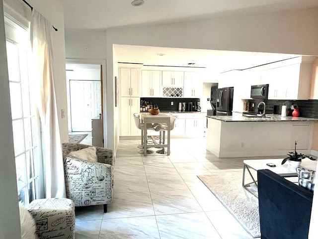 kitchen with backsplash, vaulted ceiling, white cabinetry, sink, and black appliances