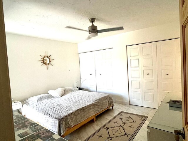 bedroom with multiple closets, light tile patterned floors, and ceiling fan