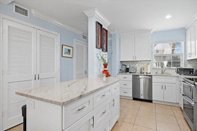 kitchen with light stone countertops, stainless steel appliances, sink, decorative backsplash, and white cabinetry