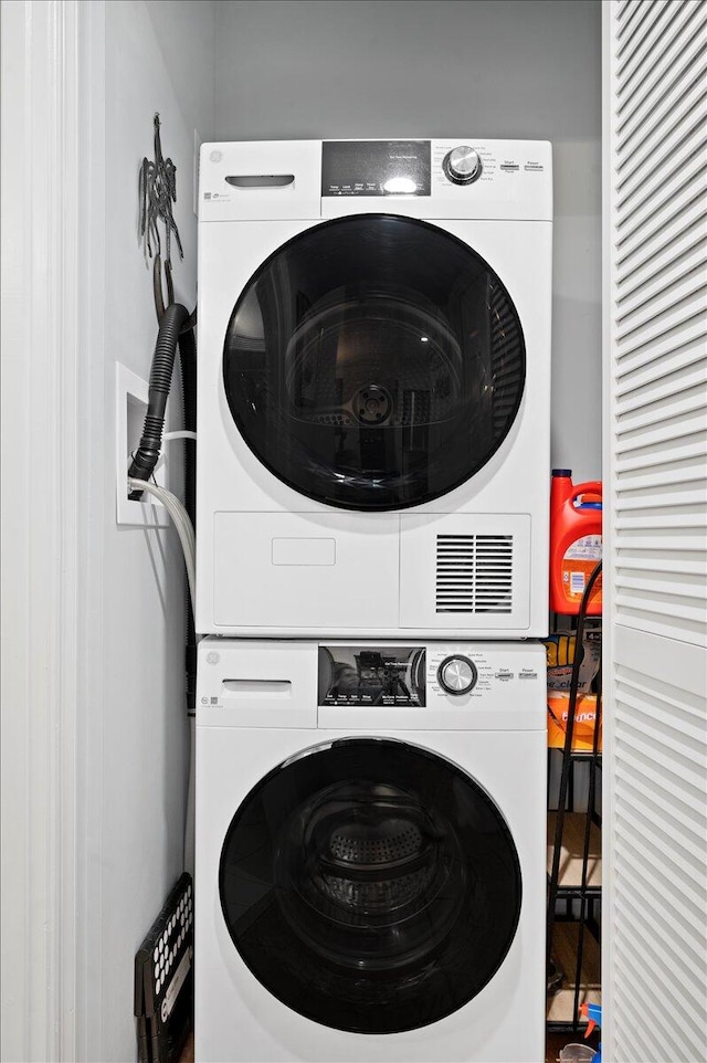 clothes washing area with stacked washer / dryer