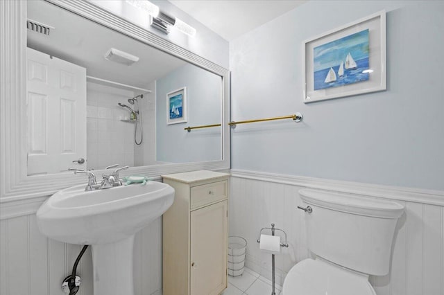 bathroom with tiled shower, toilet, sink, and tile patterned flooring