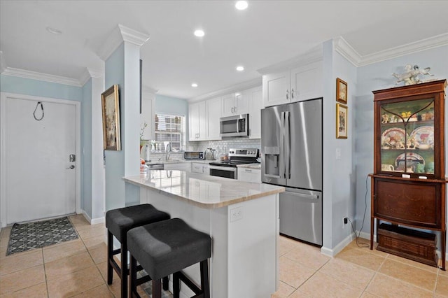 kitchen featuring a breakfast bar area, light stone countertops, light tile patterned floors, stainless steel appliances, and white cabinetry