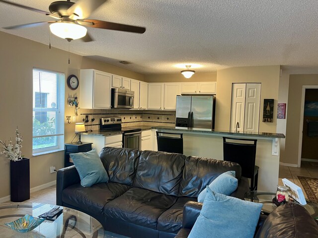 living room featuring light tile patterned floors, a textured ceiling, and ceiling fan