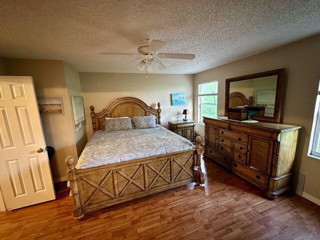 bedroom with ceiling fan, dark hardwood / wood-style flooring, and a textured ceiling