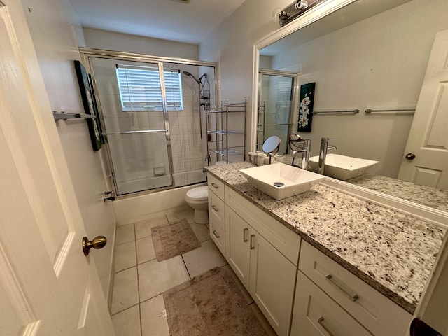 bathroom with tile patterned floors, toilet, combined bath / shower with glass door, and vanity