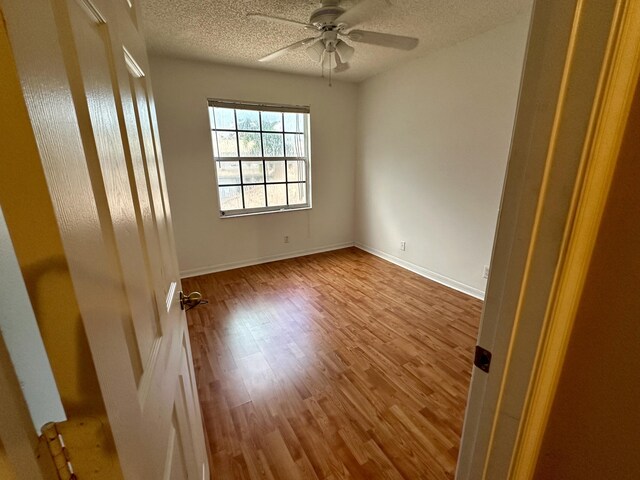 spare room featuring hardwood / wood-style flooring, ceiling fan, and a textured ceiling