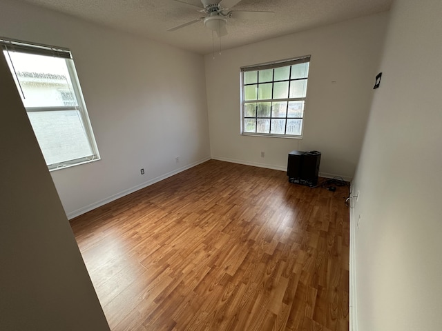 empty room featuring baseboards, wood finished floors, and a ceiling fan