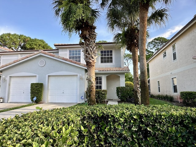 view of front of property with a garage, stucco siding, a tile roof, and concrete driveway