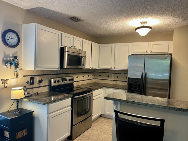 kitchen featuring appliances with stainless steel finishes, visible vents, tasteful backsplash, and white cabinets